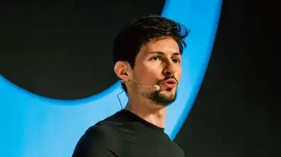 Pavel Dourov s’exprime sur scène avec un micro-casque, sur fond bleu, visage concerné